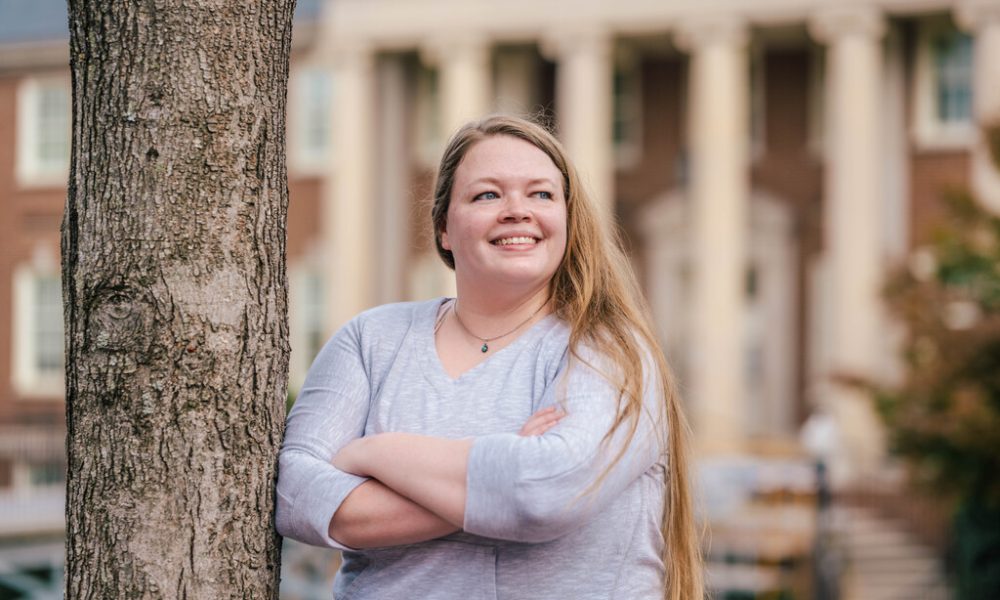 Sarah Robinson, the first Arch MI Scholar at UNCG smiling while leaning against a tree.