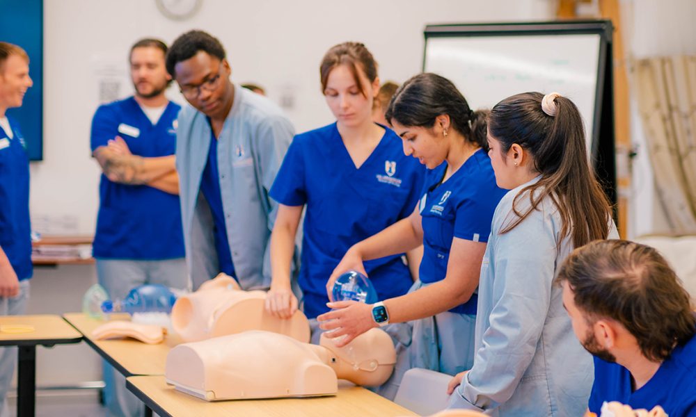 UNCG Nursing Students practicing CPR techniques on a mannequin.